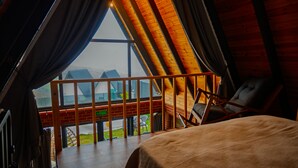 A bedroom with a large window, a bed, and a chair.