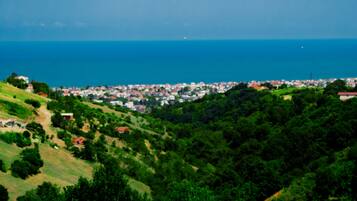 Un paisaje costero con un pueblo en el valle, colinas verdes y el mar.