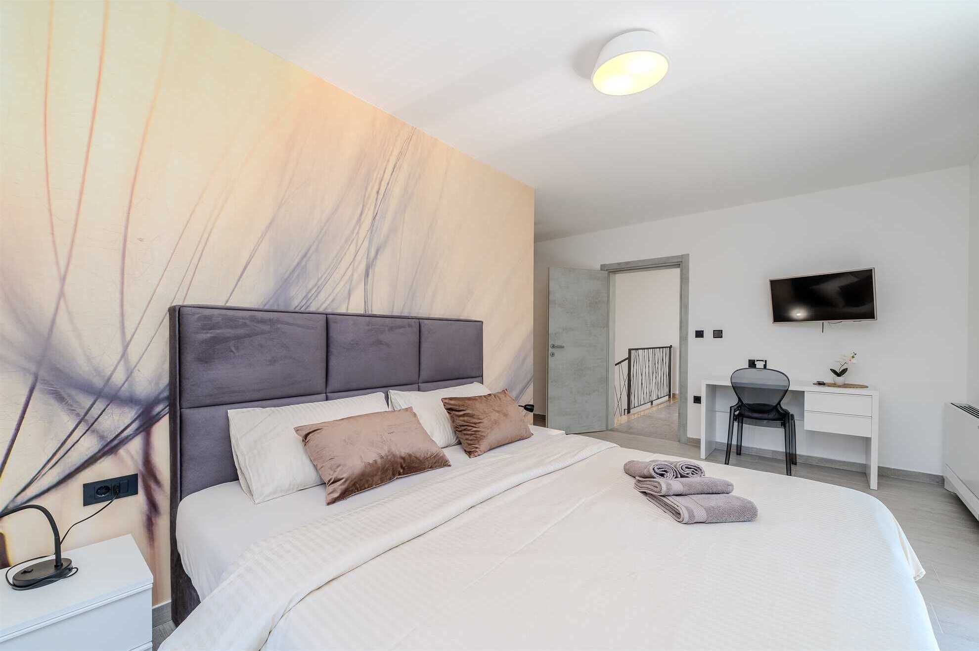 Une chambre à coucher moderne avec un lit, une table de chevet et un bureau avec une chaise.