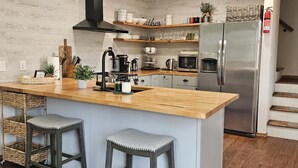 A modern kitchen with a wooden island, bar stools, stainless steel appliances, and a built-in stove. - Arrowhead Community Hot Tub Firepit Game Rm Movie Rm Fireplace Walk 2 Pool, Lake (Pocono Lake)