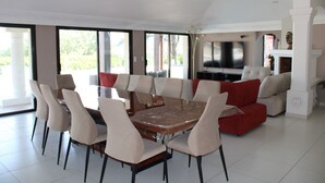A spacious living area with a large dining table surrounded by chairs, a red sofa, and a television. - 10-PERSON VILLA WITH LARGE POOL NEAR ROCK AND LAKE (Roquebrune-sur-Argens)