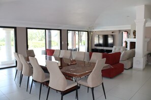 Ein geräumiger Wohnbereich mit einem großen Esstisch, umgeben von Stühlen, einem roten Sofa und einem Fernseher.