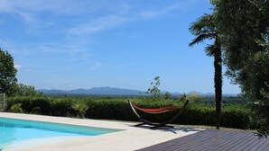 A swimming pool with a hammock and a view of distant mountains. - 10-PERSON VILLA WITH LARGE POOL NEAR ROCK AND LAKE (Roquebrune-sur-Argens)