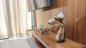 Ein Holzkonsolentisch mit Dekorationsobjekten und einem an der Wand montierten Flachbildfernseher.