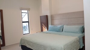 Ein Schlafzimmer mit einem Bett, einem Fenster und einem an der Wand hängenden Kunstwerk.