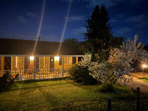 A building with a covered outdoor area, a fenced garden, and a tree with white blossoms. - Maison Marly | Jacuzzi & Castle View by Dordogne (Castelnaud-la-Chapelle)