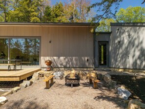A modern outdoor area with a wooden deck, a fire pit, and a grill. - The Lost Lake Residence (Wentworth-Nord)