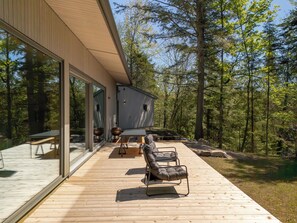 A modern house with a deck, large glass windows, and a view of a forest. - The Lost Lake Residence (Wentworth-Nord)