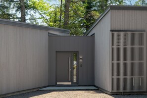 A modern building with a dark door, a small porch, and a window. - The Lost Lake Residence (Wentworth-Nord)