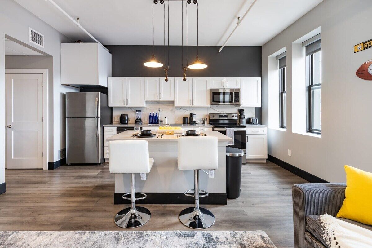 A modern kitchen with a central island, stainless steel appliances, and pendant lighting.