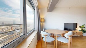 A modern room with a large window, a round table, and a flat-screen TV. - Modern Studio Zurich Center (Zürich)