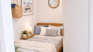A bedroom with a bed, bedside table, lamp, and a hanging basket. - Modern Studio Zurich Center (Zürich)
