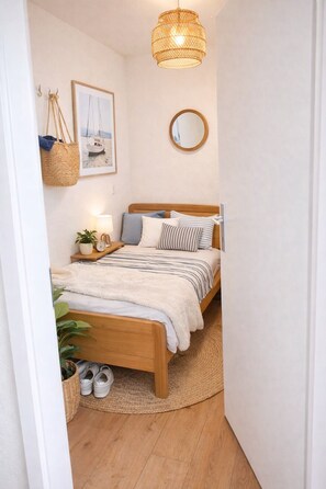 A bedroom with a bed, bedside table, lamp, and a hanging basket. - Modern Studio Zurich Center (Zürich)