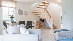 Un interior moderno con escalera, comedor y zona de estar.