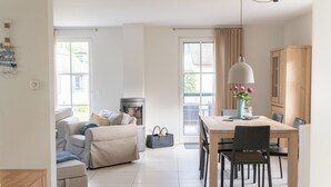 Una sala de estar moderna con chimenea, un comedor con mesa y sillas, y una cocina con armarios de madera.