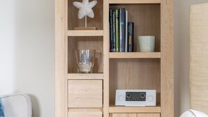 Una estantería de madera con adornos, libros y un radio.