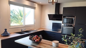 Een moderne keuken met een groot raam, inbouwapparatuur en een houten eiland.