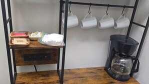 Una cocina con cafetera, microondas y estantes con tazones y tazas.