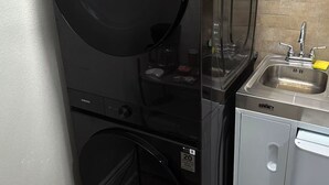 Un área de lavandería compacta con lavadora, secadora y un lavamanos pequeño.