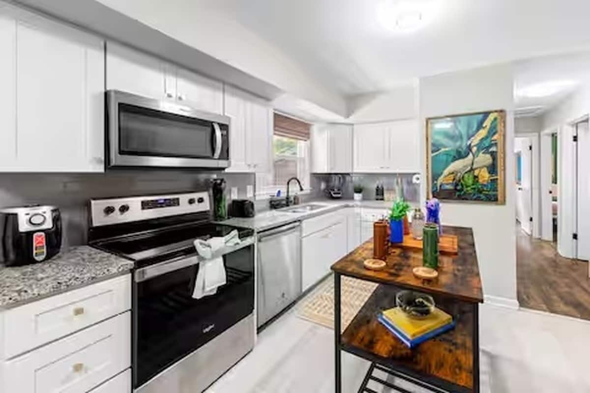 Una cocina moderna con armarios blancos, electrodomésticos de acero inoxidable y una isla de madera.
