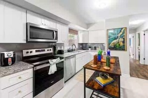A modern kitchen with white cabinetry, a microwave, an oven, and a coffee maker.