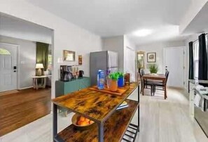 A modern kitchen with a wooden table, a refrigerator, and a dining area with chairs.