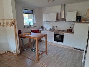 Een moderne keuken met witte kasten, een roestvrijstalen afzuigkap en een houten eettafel.