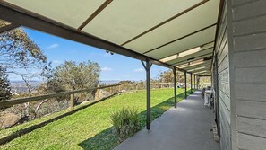 A covered outdoor area with a view of a grassy field and distant hills.