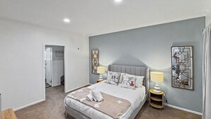 Un dormitori amb un llit, làmpades de nit, un mirall i una porta que dona a un bany.