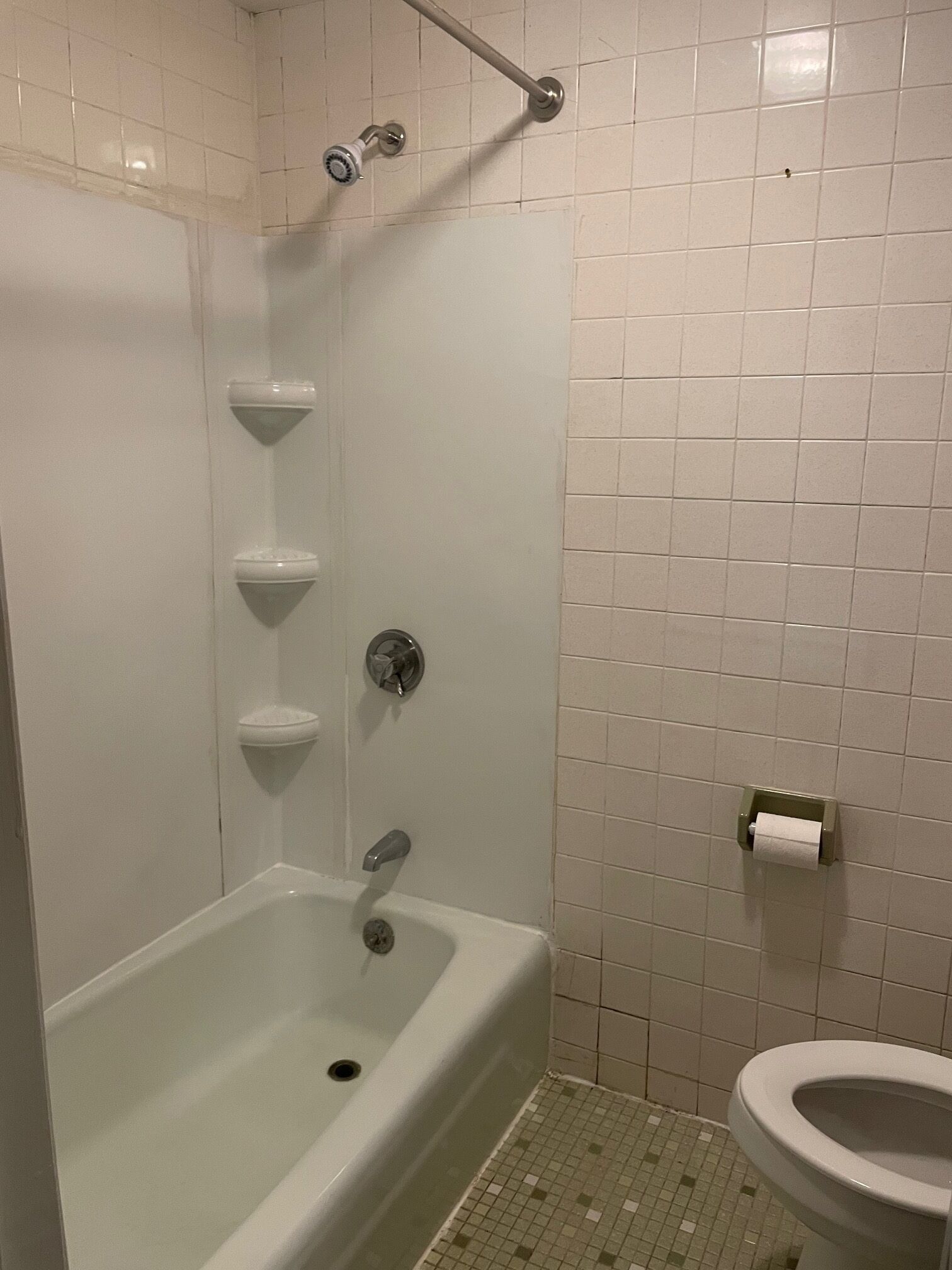 A bathroom with a bathtub, a toilet, and a showerhead.