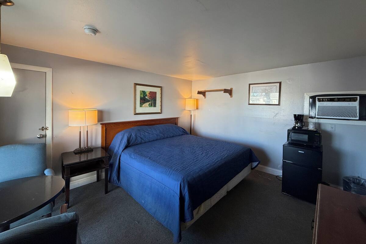A hotel room with a bed, bedside tables, lamps, a coffee maker, and a microwave.