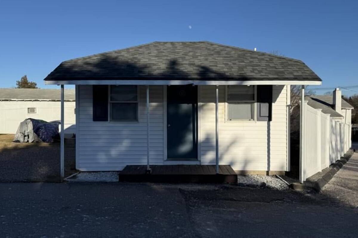 A single-story mobile home with a dark roof, a front door, and a small porch.