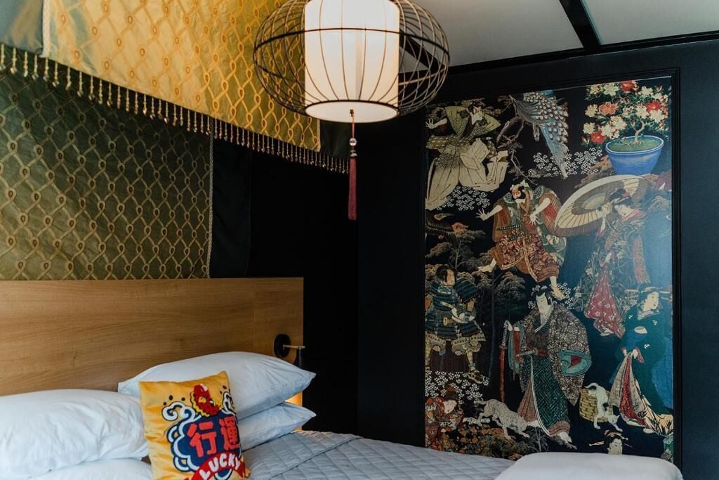 Una habitación con una cama, un candelabro colgante, un tapiz y una almohada decorada.