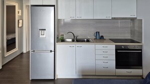 A modern kitchen with a built-in refrigerator, a sink, a stove, and white cabinetry. - Blue Bay Suites (Myloi)