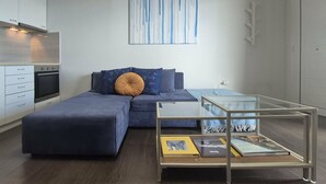 A modern living room with a sofa, a glass coffee table, and a bookshelf. - Blue Bay Suites (Myloi)