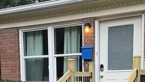 Una casa con puerta principal, buzón y escaleras de madera que conducen a la entrada.