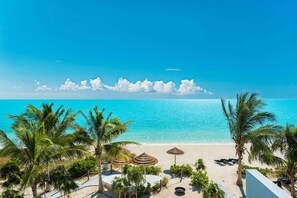 A beach with palm trees, a clear sky, and a view of the ocean. - Villa Blue Lagoon 4 BR (Long Bay)