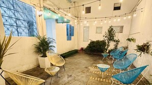 En udendørs terrasse med siddepladser, lyskæder og plantekasser.