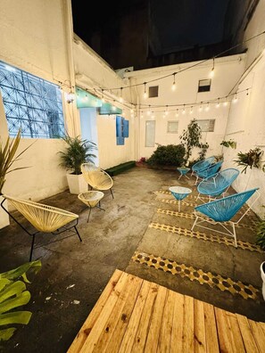 Eine Terrasse im Freien mit Sitzgelegenheiten, Lichterketten und Kübelpflanzen.