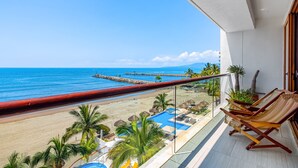 Ein Balkon mit Blick auf den Strand, Liegestühlen und einem Poolbereich.