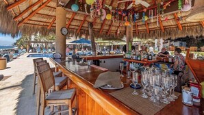Eine Bar mit Holzmöbeln, einem Pool und einem Reetdach.