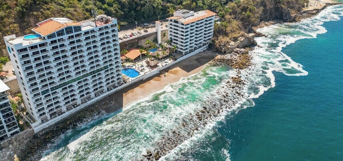 A coastal hotel with multiple balconies, a pool, and a beachside location.