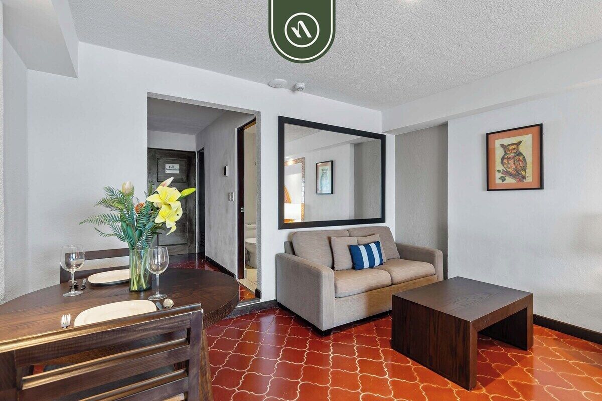 Un salon moderne comprenant un coin repas, un canapé, une table basse et un miroir au mur.