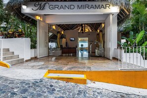 The entrance to Grand Miramar with a thatched roof, a reception desk, and a staircase leading inside. - Upscale Bayview Villa With hot Tub, Private Terrace, Pool & Stylish Interiors (Puerto Vallarta)
