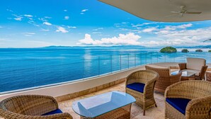 A balcony with wicker furniture, a glass table, and a view of the ocean. - Oceanfront, 8th-floor Condo With Pool, Pool spa & Large Balcony (Puerto Vallarta)
