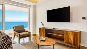 A modern living room with a large TV, wooden furniture, and a view of the sea. - Oceanfront, 8th-floor Condo With Pool, Pool spa & Large Balcony (Puerto Vallarta)