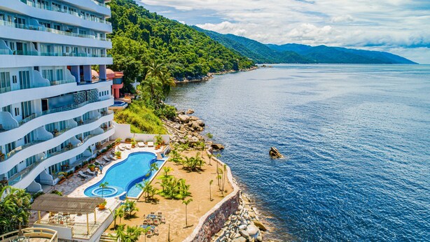 Un complexe hôtelier doté d’une piscine, d’une plage et offrant une vue sur la mer et les montagnes.
