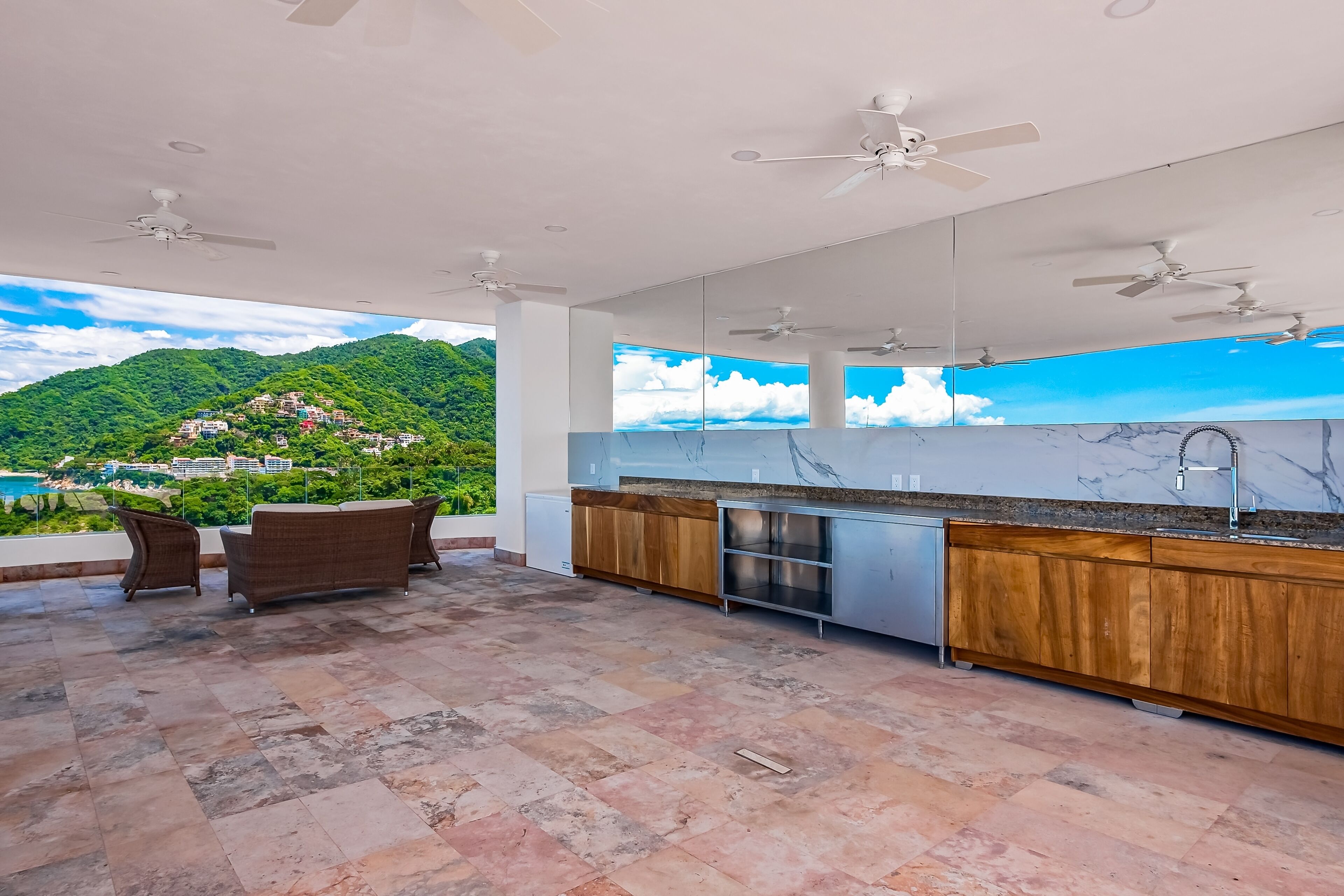 A modern kitchen with a large island, wooden cabinets, and a view of a mountainous landscape.