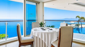 A dining area with a table set for four, overlooking a pool and the sea. - Elegant Hillside Villa With Panoramic Views, Pool, hot tub & Luxe Interiors (Puerto Vallarta)