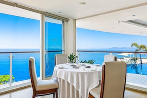 Ein Essbereich mit einem Tisch für vier Personen mit Blick auf einen Pool und das Meer.